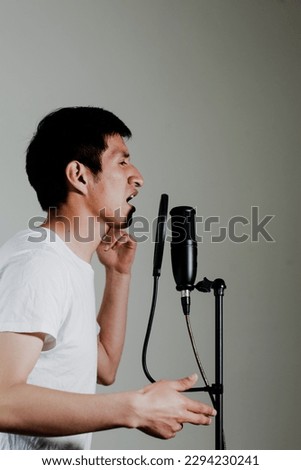 Photograph of male singer in a recording studio with dramatic lighting in the background. Concept of people, music and arts.