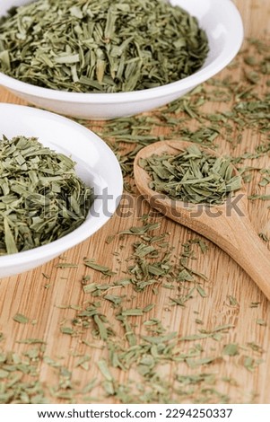 A pile of dried Tarragon Leaves isolated on a wooden cutting board with copy space Royalty-Free Stock Photo #2294250337