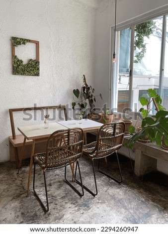 A rustic industriap tropical interior design, with rattan and wooden chairs. There is a unique photo frame with leaves. An interior design idea.