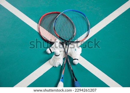 Badminton rackets and white cream badminton shuttlecocks after playing or after games on green floor in indoor badminton court, soft focus, concept for badminton lovers around the world. Royalty-Free Stock Photo #2294261207