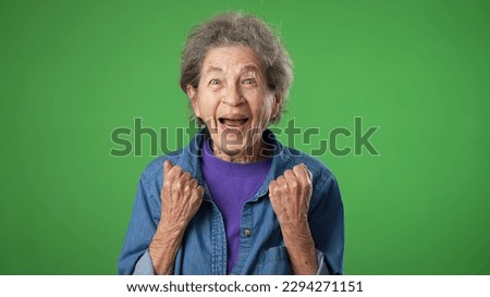 Portrait of excited, surprised saying WOW smiling elderly senior old woman with wrinkled skin and grey hair smiling isolated on green screen background studio