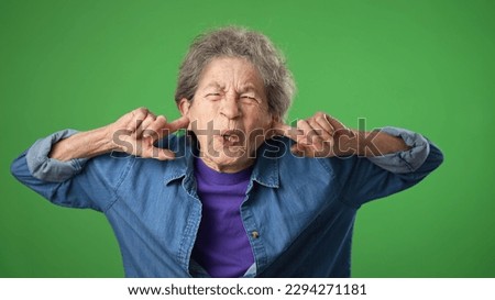 Displeased irritated frustrated sad angry elderly senior woman with wrinkled skin and grey hair closed eyes cover ears do not want to listen scream isolated on green screen background studio portrait Royalty-Free Stock Photo #2294271181