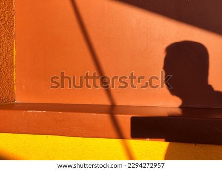 Shadow of a man on the brown and yellow wall.