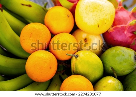 Colorful mixed fruits such as bananas, oranges, dragon fruit, pears, guava