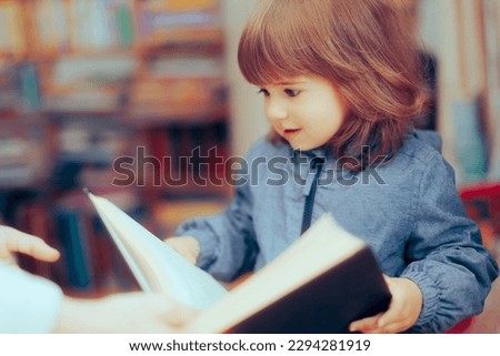 
Little Toddler Girl Checking a Book in a Library. Curious cheerful little kid looking at a picture book in a bookstore
