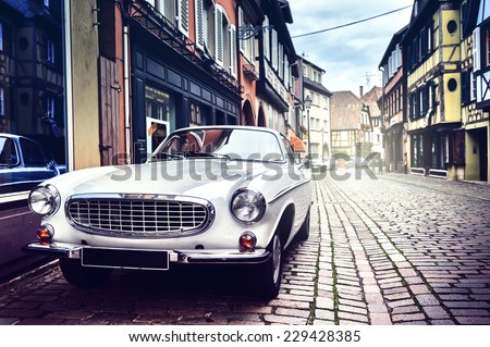 Retro car parked in old European city street Royalty-Free Stock Photo #229428385