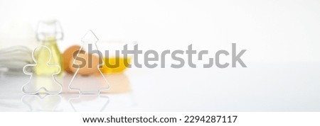 christmas Dessert ingredients and utensils on white reflect table background . Front view. Copy space. egg, flour, milk, oil, cookies cutter pine gingerbread man.Banner Royalty-Free Stock Photo #2294287117