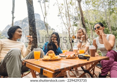 Four international friends having a party during summer in the nature spot, drinking juice and eating melons