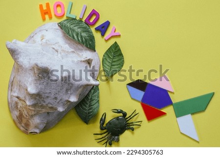 Holiday letters with seashells cassis cornuta, crab, leaves and fish made from tangram pieces. Beach holiday concept on yellow background