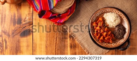 Pork rinds stewed in red sauce accompanied by rice and refried beans. Traditional homemade dish very popular in Mexico, this dish is part of the popular Tacos de Guisado.
