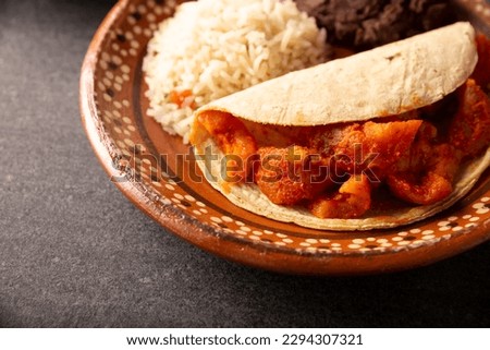 Pork rinds in red sauce Taco accompanied by rice and refried beans. Traditional homemade dish very popular in Mexico, this dish is part of the popular Tacos de Guisado.