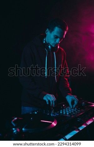 Young white man performing as a DJ in night club. Professional disk jokey mixing vinyl records on a concert