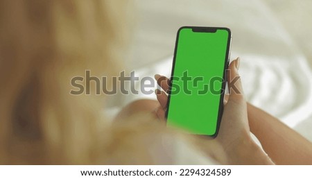 A woman holds a mobile phone in her hands. Use green screen for close-up copy space.