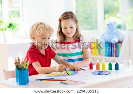 Kids paint. Child painting in white sunny study room. Little boy and girl drawing rainbow. School kid at art homework. Arts and crafts for kids. Paint on children hands. Creative little artist at work