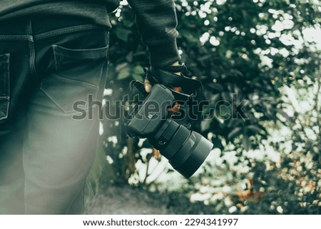 Hand holding professional Camera, Nature Photography day concept image, Photographer with camera, World Photo Day