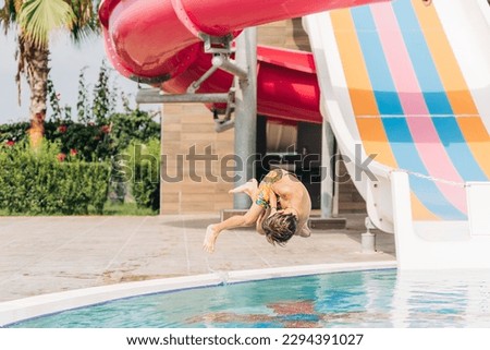 Child jumping and dives in swimming pool at sunny day. Kid boy refreshing and playing at heat weather, active vacation and healthy lifestyle. Happy summer. Royalty-Free Stock Photo #2294391027