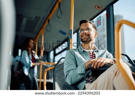 Low angle view of happy man riding in a bus. Copy space.  Royalty-Free Stock Photo #2294396203