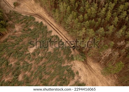 Drone photography of forestry machine piking up small trees and transporting during cloudy spring dawn.