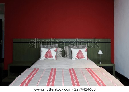 Interior of a hotel bedroom with red wall and white bedding