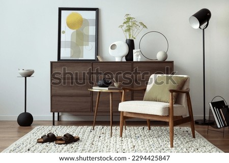 Elegant composition of living room interior with beige armchair with mock up poster frame, pillow, carpet, coffee table and commode with personal accessories. Home decor. Template. Royalty-Free Stock Photo #2294425847
