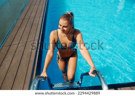 Happy woman getting out of the water while spending summer day at swimming pool. Copy space.
