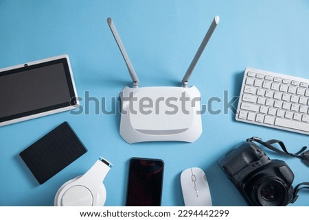 Wi fi router with a tablet, phone, computer keyboard and other objects.
