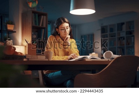 Young university student reading books late at night, she is studying and preparing for her exams Royalty-Free Stock Photo #2294443435