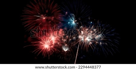 Red, white, and blue fireworks light up the night sky, patriotic celebration, New Years Eve or Independence Day. Shallow depth of field.  Royalty-Free Stock Photo #2294448377