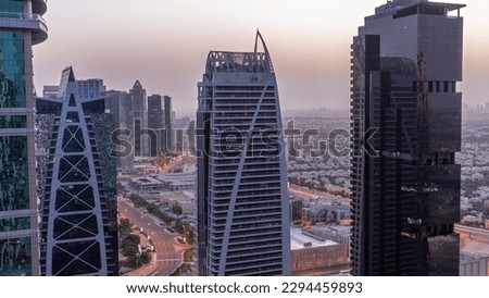 Tall residential buildings at JLT district aerial night to day transition , part of the Dubai multi commodities centre mixed-use district. Villa houses and road traffic on a background