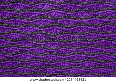 Purple grey crocheted wave pattern. Knitted texture.