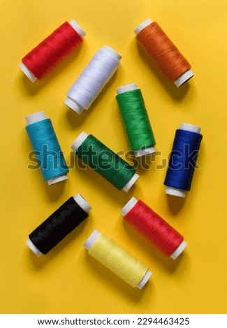 Multicolored sewing threads on a yellow background. Top view.