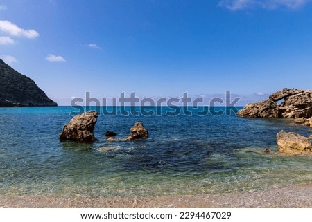  A beautiful landscape of the coast of the island of Corfu in the Ionian Sea of the Mediterranean in Greece. Pure blue clear water washes over the shores of the Greek island.