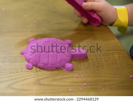 The child made a turtle out of sand on the table. High quality photo