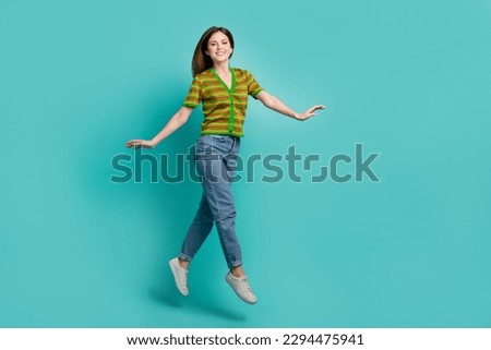 Full length photo of sweet shiny lady wear striped cardigan jumping high walking empty space isolated turquoise color background