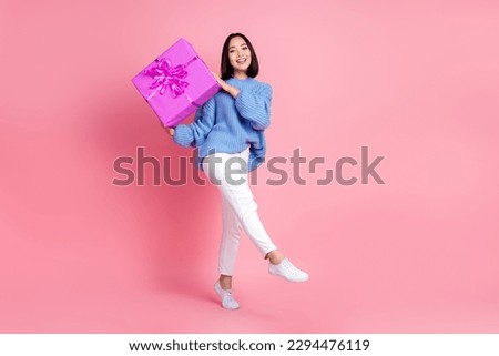 Full body portrait of pretty cheerful lady arms hold giftbox walk isolated on pink color background