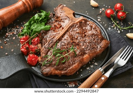 Steaks T-bone. Sliced beef grilled T-bone or porterhouse meat steak with spices rosemary and pepper on black marble board on old wooden background. Top view. Mock up. Royalty-Free Stock Photo #2294492847