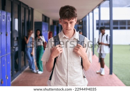 Unhappy Teenage Boy Outdoors At High School Being Teased Or Bullied Royalty-Free Stock Photo #2294494035