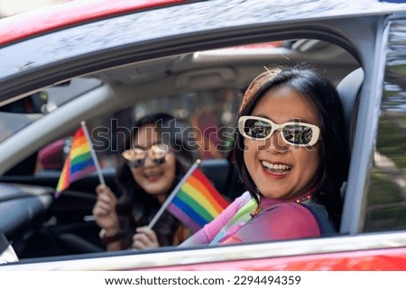 Happy Asian woman support LGBT pride parade in car. with Rainbow of LGBTQ or LGBTQIA 