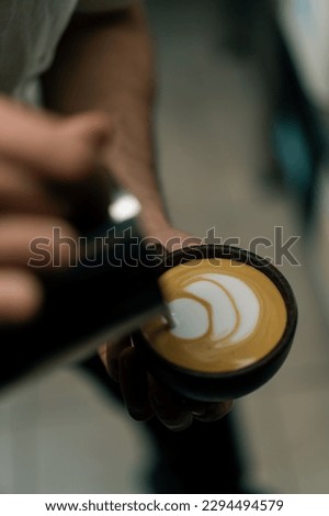 Barista making latte art in a cafe Male hands pouring steam of milk into a cup of Cappuccino with pattern