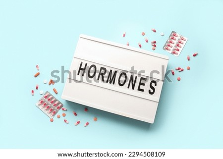 Board with word HORMONES and pills on blue background Royalty-Free Stock Photo #2294508109