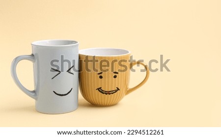 Cups with happy faces for Friendship Day on beige background Royalty-Free Stock Photo #2294512261