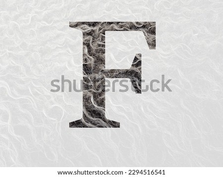Letter F of the alphabet made with curly hear of the wool of a sheep, with colors brown, white and beige