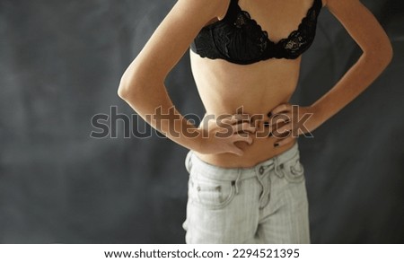 Anorexia, bulimia and stomach of woman in studio for weight, obsession and starvation on black background. Eating disorder, mental illness and girl waist suffering body dysmorphia, comparison or loss Royalty-Free Stock Photo #2294521395