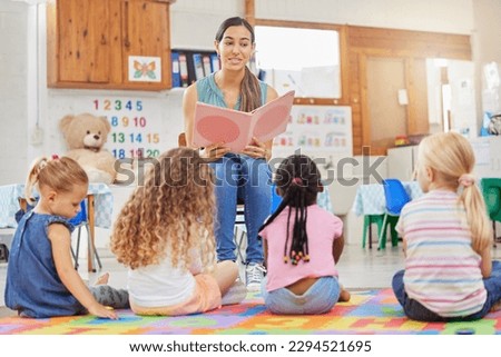 Everyone loves story time. Shot of a young woman reading to her preschool students. Royalty-Free Stock Photo #2294521695