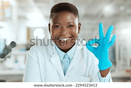 Ive got it from here. Shot of an attractive young scientist sitting alone in her laboratory and making an okay sign.