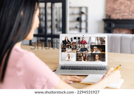 Back view of female employee, team working by group video call share ideas, brainstorming, negotiating use video conference, pc screen view nine multi ethnic young people, comfortable application