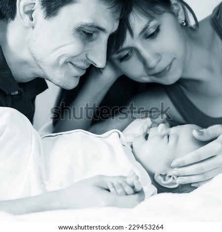 Smiling young couple and a little baby in bed at home