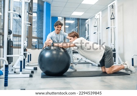 Experienced instructor assisting a man in a rehabilitation workout Royalty-Free Stock Photo #2294539845