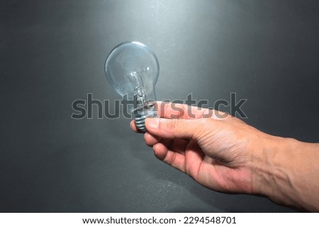 Hand holding light bulb. Idea concept with innovation and inspiration. Isolated on black background.