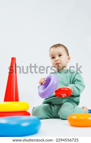 Little boy playing logic educational games with plastic pyramid isolated on white background. A happy child plays with an educational toy. The baby is one year and four months old